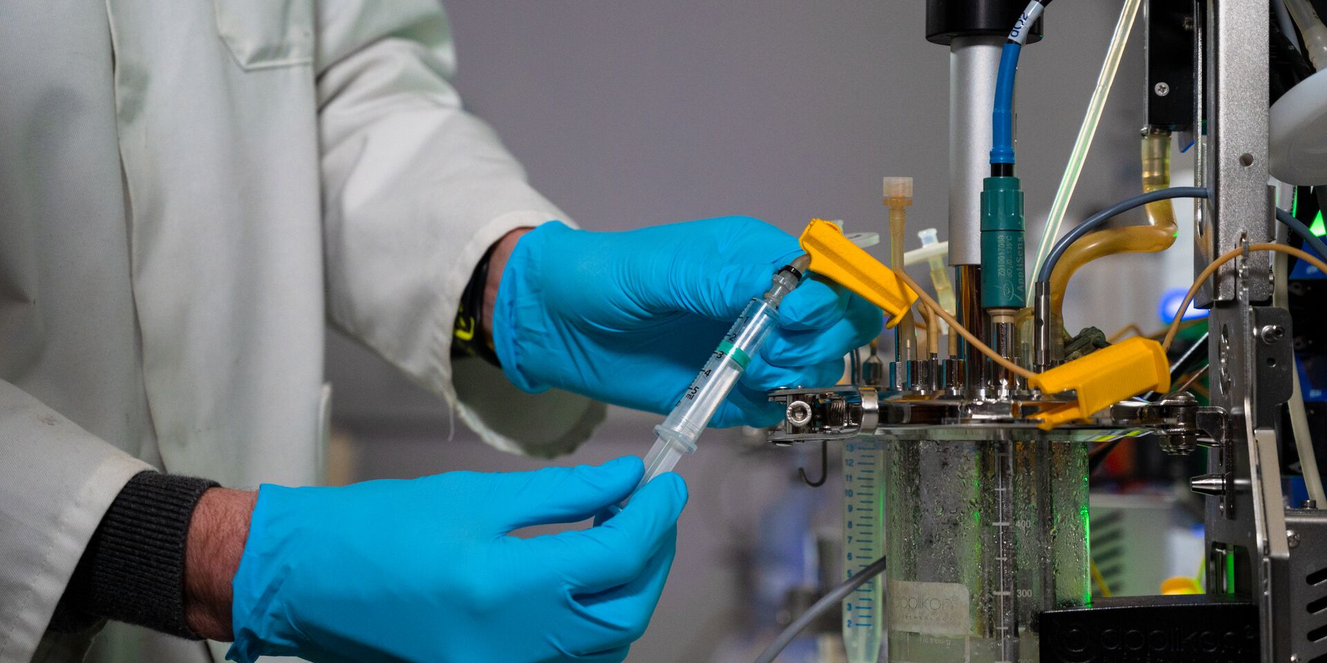 Scientist with gloves checking a syringe